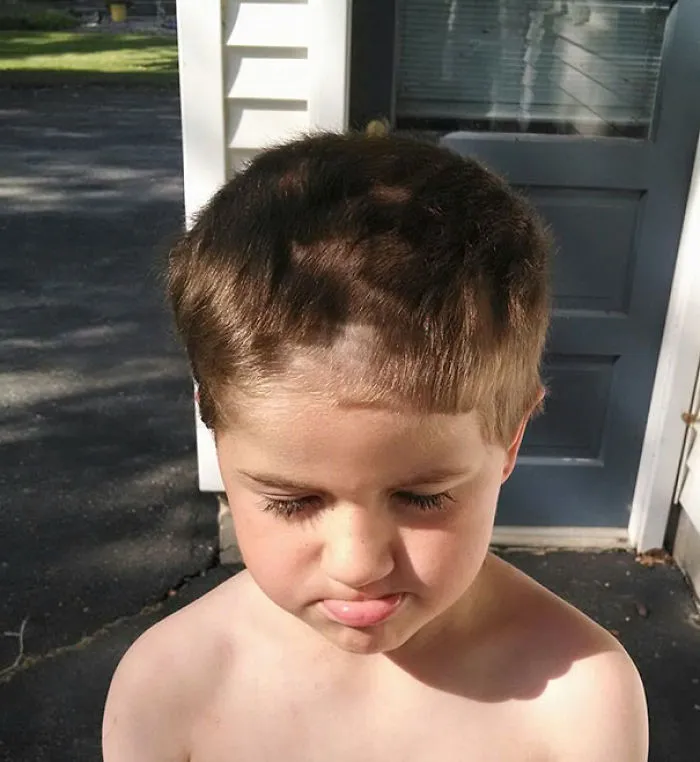 Child with uneven haircut, looking regretful after self hair-cutting attempt.