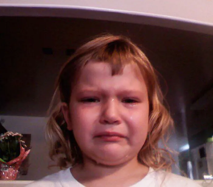 Child with uneven haircut, visibly upset after cutting their own hair.