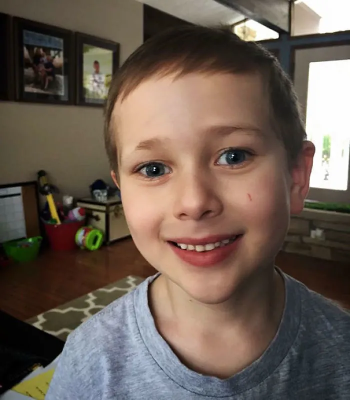 Child with self-cut hair and a smile, experiencing a haircut regret moment at home.