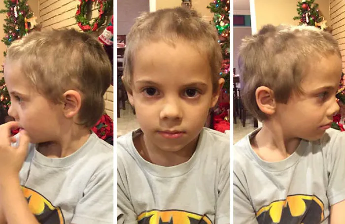 Child with a self-cut hairstyle looking regretful, wearing a Batman shirt, with Christmas decorations in the background.