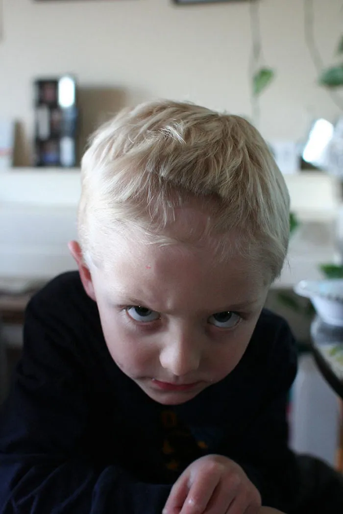 Child with a self-cut hairstyle looking regretful, illustrating kids’ hair decisions gone wrong.