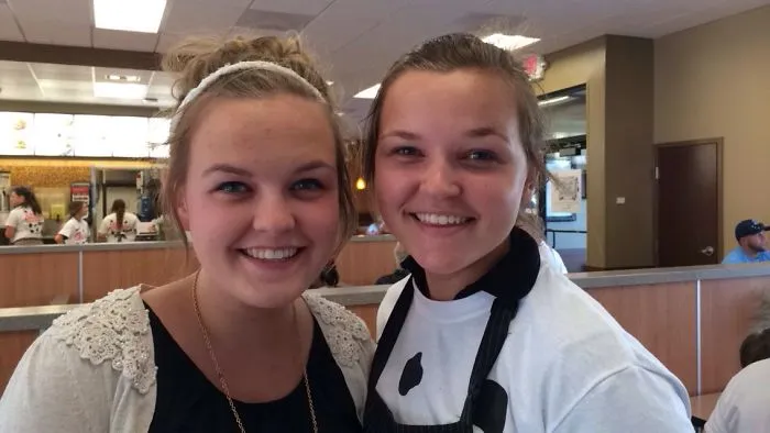Two women smiling in a restaurant, showcasing real-life doppelgangers.