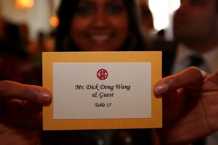 Person holding a place card for Mr. Dick Dong Wang, showcasing funny names at a formal event.