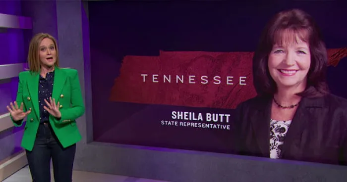 TV host in a studio next to a screen displaying the name Sheila Butt, highlighting funny names.