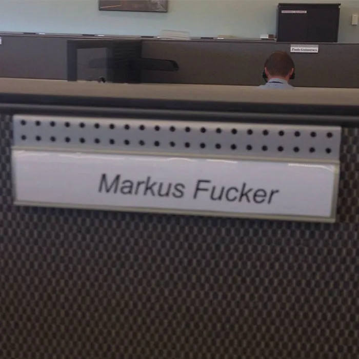 Funny nameplate with humorous name in an office cubicle setting.