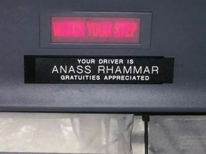 Bus driver's name tag with "Anass Rhammar" under "Watch Your Step" sign, featuring a funny name.