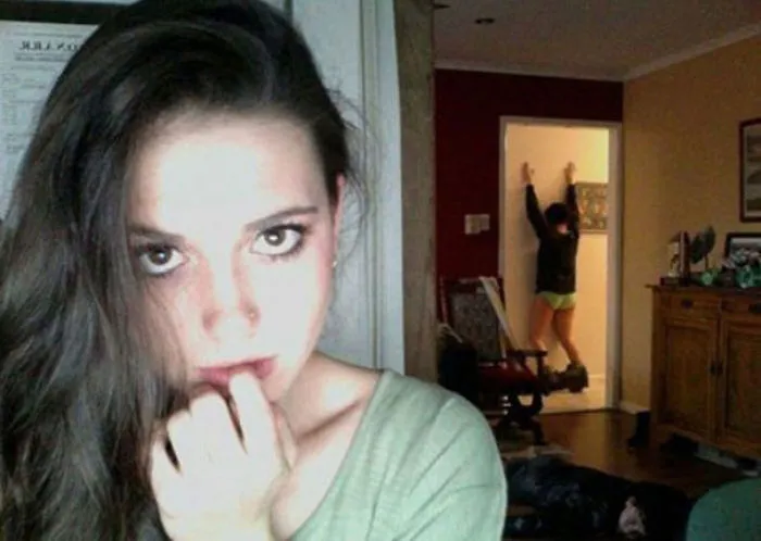 Woman taking selfie a person with dropped pants on the background