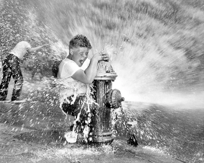 Youngster Playing In Water From Fire Hydrant. Police Are Waging Campaign Against Indiscriminate Opening Of Hydrants Since It Reduces Water Pressure And Poses A Threat To Fire Fighters, New York, 1959