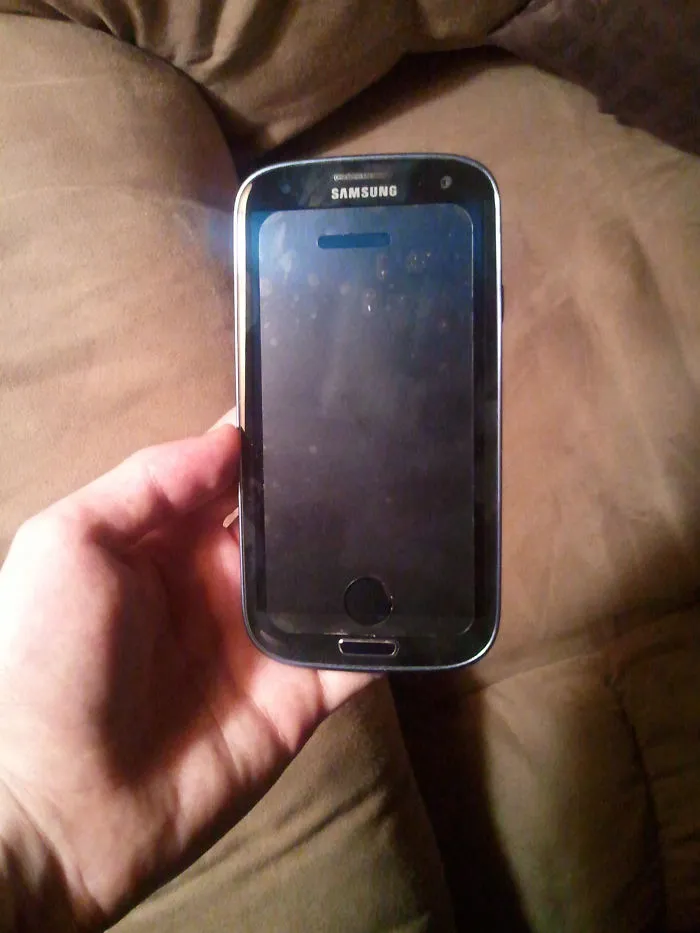 Hand holding a Samsung phone upside down, illustrating technology fails by older people.