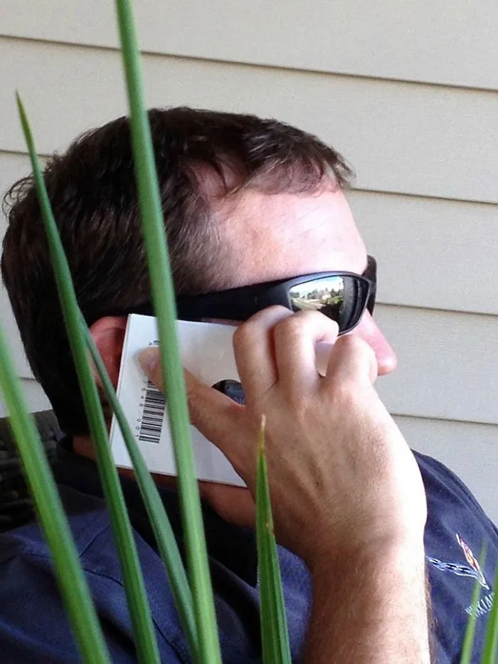 An older person using a packaged item as a cell phone, illustrating a humorous technology fail.
