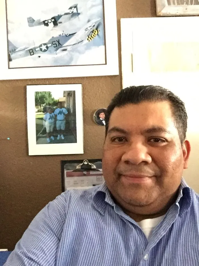 Man taking a selfie indoors with framed pictures on the wall, unrelated to people photoshopping Mr. Bean into things.