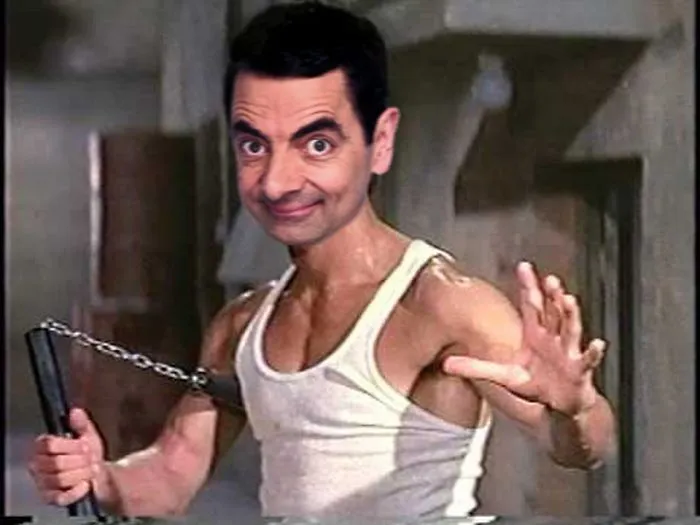 Photoshopped image of Mr. Bean with a muscular body holding nunchucks in a white tank top, humorously edited.