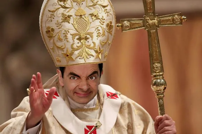 Mr. Bean photoshopped wearing a pope outfit holding a golden cross in a humorous and hilarious scene.