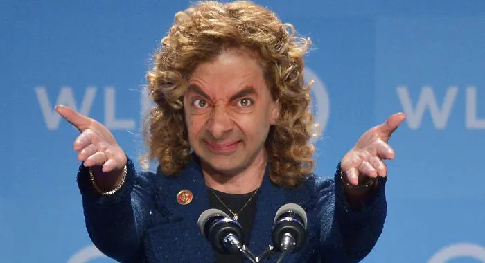 Mr Bean photoshopped with curly hair speaking at a podium with two microphones, captured in a humorous pose.
