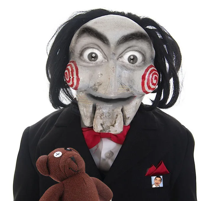A creepy puppet wearing a suit with Mr. Bean’s eyes and mouth photoshopped onto its face, holding a teddy bear.