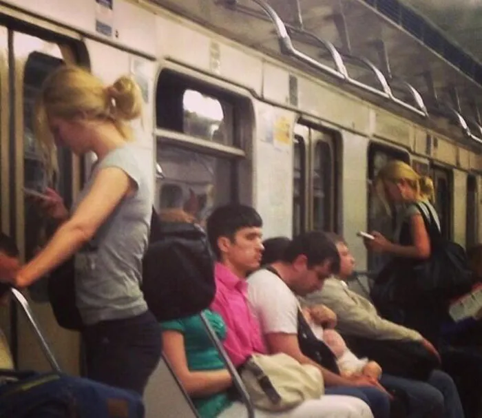 Two girls standing in the train and wearing same shirts and have same hairstyle