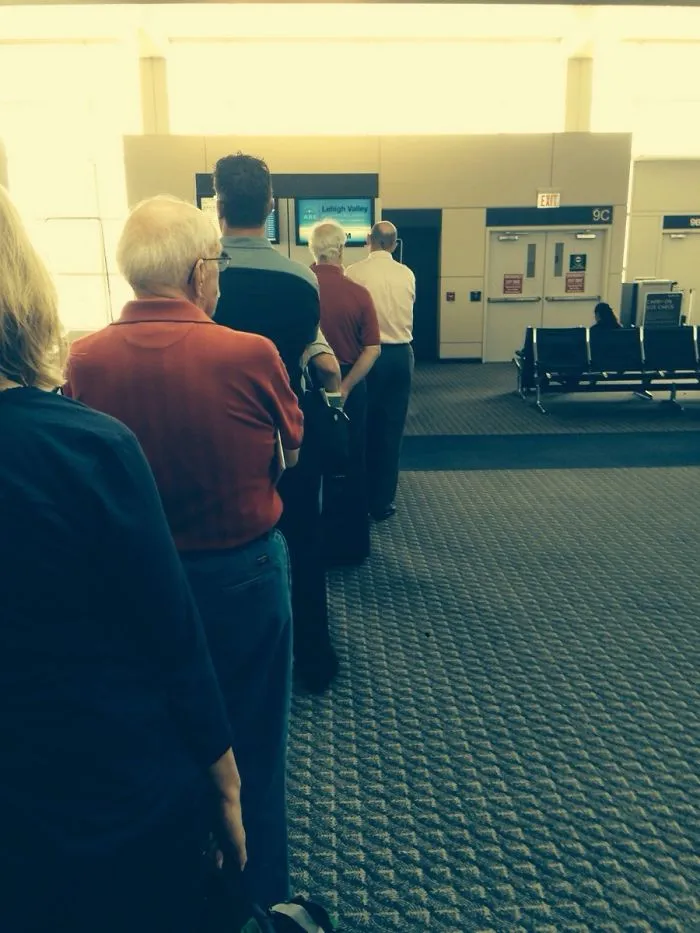 Two mans standing in the line and wearing same clothes