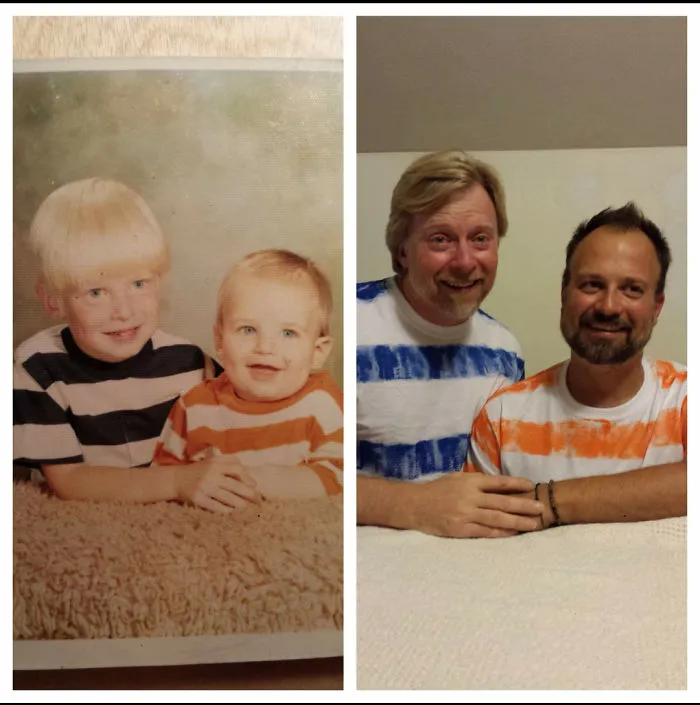 Two siblings in matching striped shirts recreating old childhood photo