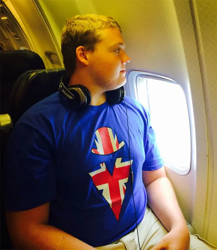 Tall person wearing headphones and a British flag shirt sitting by the airplane window, highlighting everyday struggles of tall people.