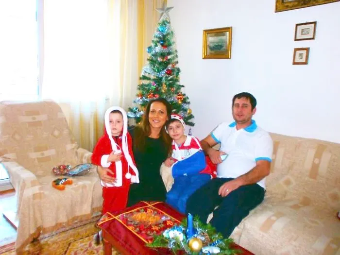 Family with kids celebrates Christmas posing by decorated tree indoors