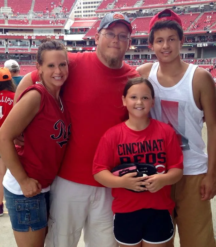 Family at baseball stadium wearing Cincinnati Reds apparel