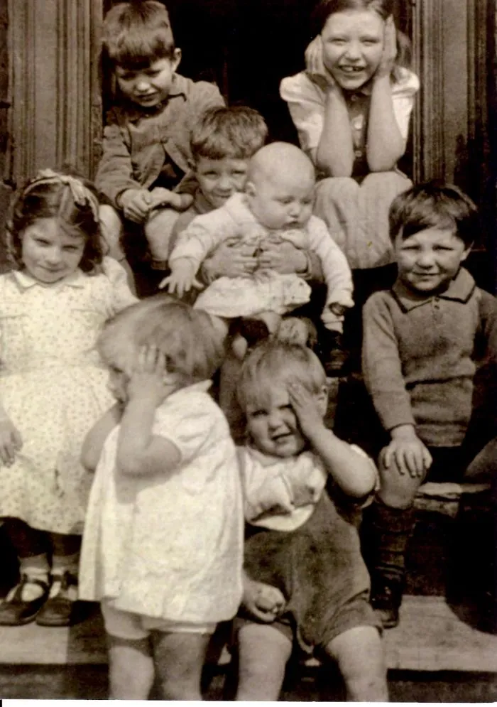 Vintage group of children pose on steps with playful expressions