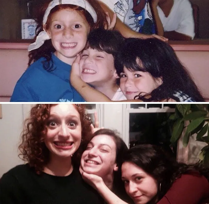 Three sisters smiling and posing while recreating a childhood photo indoors