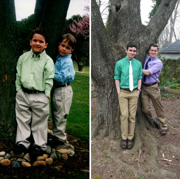 Two brothers dressed alike recreating childhood photo by leaning on tree
