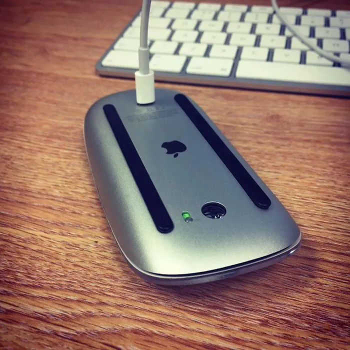 Apple mouse charging awkwardly upside down, illustrating a design fail.