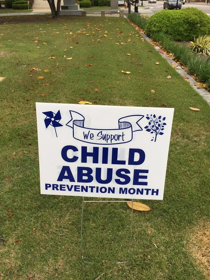 Lawn sign with a design fail: "We Support Child Abuse Prevention Month," humorous wording contradiction.