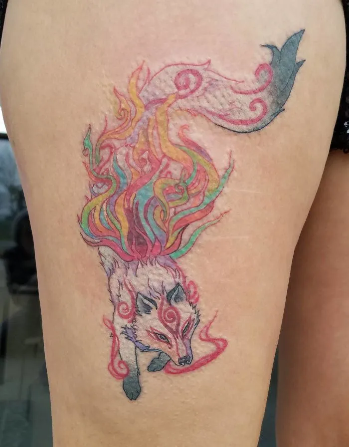 Colorful fox tattoo transforming a scar into art with vibrant flowing tails.