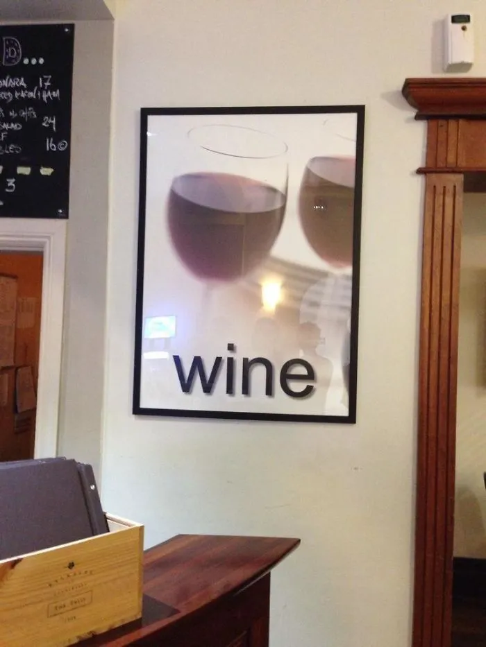 Framed picture on a wall showing upside-down wine glasses labeled "wine," a humorous design fail.