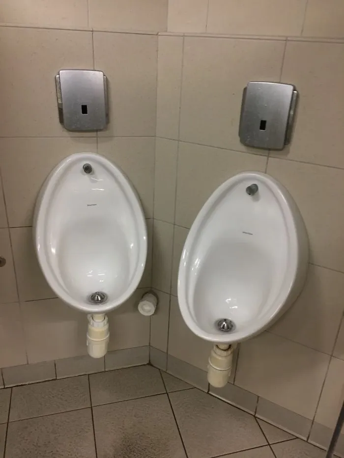 Two urinals awkwardly placed in a corner, illustrating a humorous design fail.