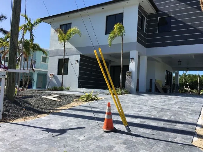 House with a driveway design fail, blocked by a pole and traffic cone.
