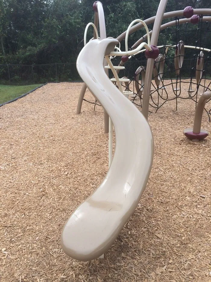 Curved playground slide with awkward twist, illustrating a design fail in an outdoor setting.