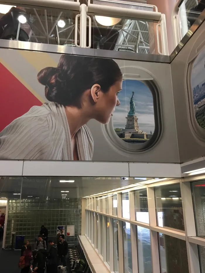Woman on a poster appears to gaze at the Statue of Liberty through a window in a funny design fail.