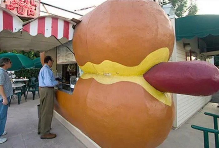 Giant hotdog-shaped food stand with people ordering, showcasing a hilarious design fail.