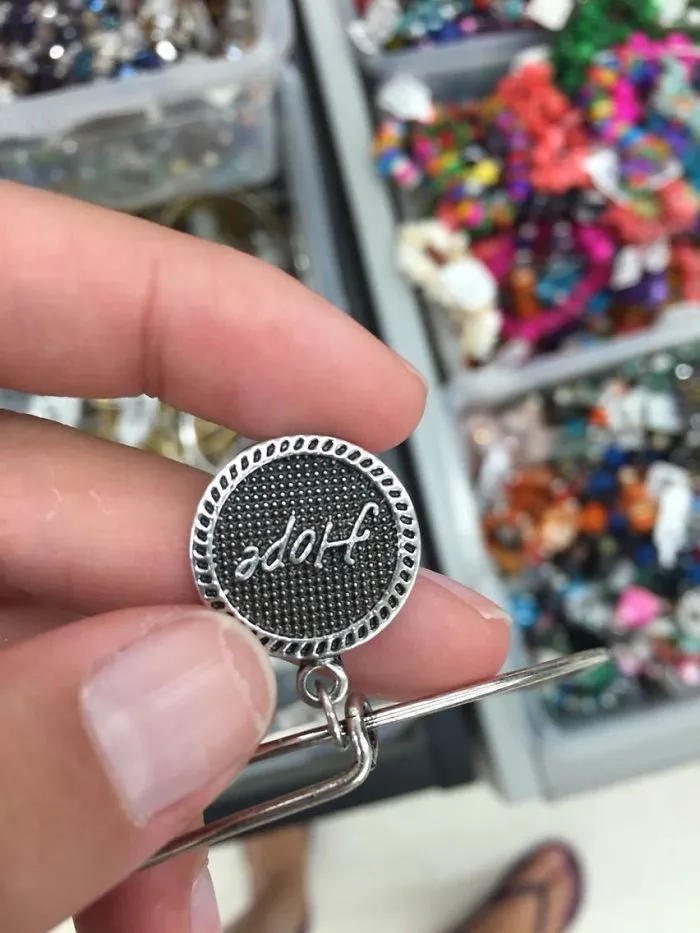 Close-up of a keychain with the word "hope" mistakenly printed upside down, showcasing a hilarious design fail.