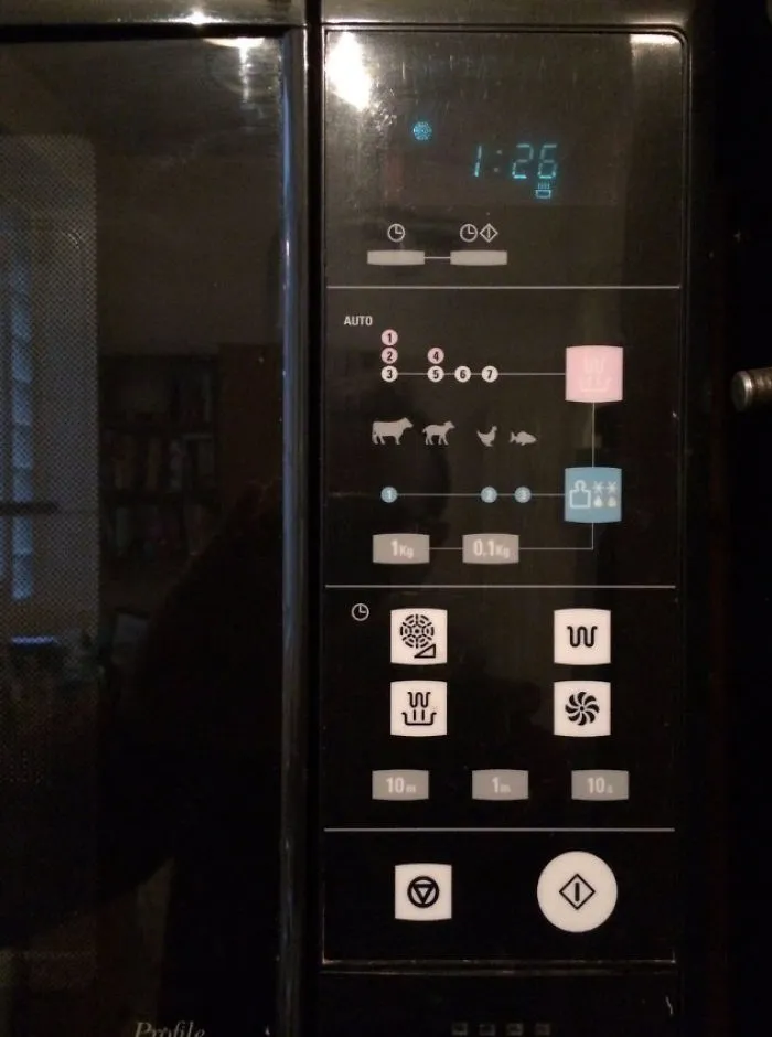 Microwave control panel with confusing symbols, showcasing a design fail.