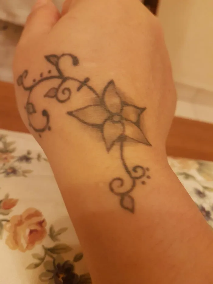 Floral tattoo covering a scar on a hand, showcasing art transformation.