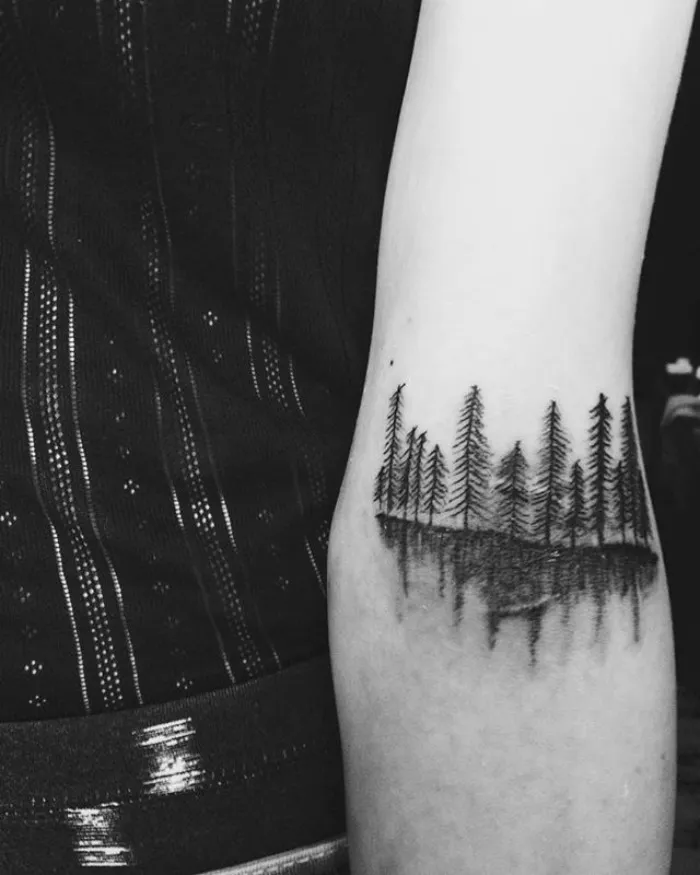 Tattoo of a forest scene creatively transforming a scar into art on an arm.