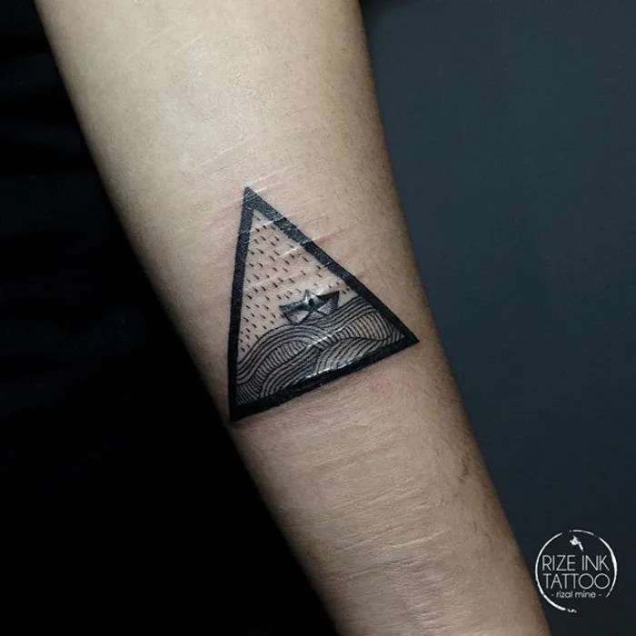 Tattoo covers scar with a geometric triangle design on forearm.