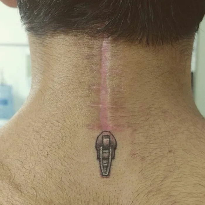Tattoo art transforming a scar into a zipper design on the back of the neck.