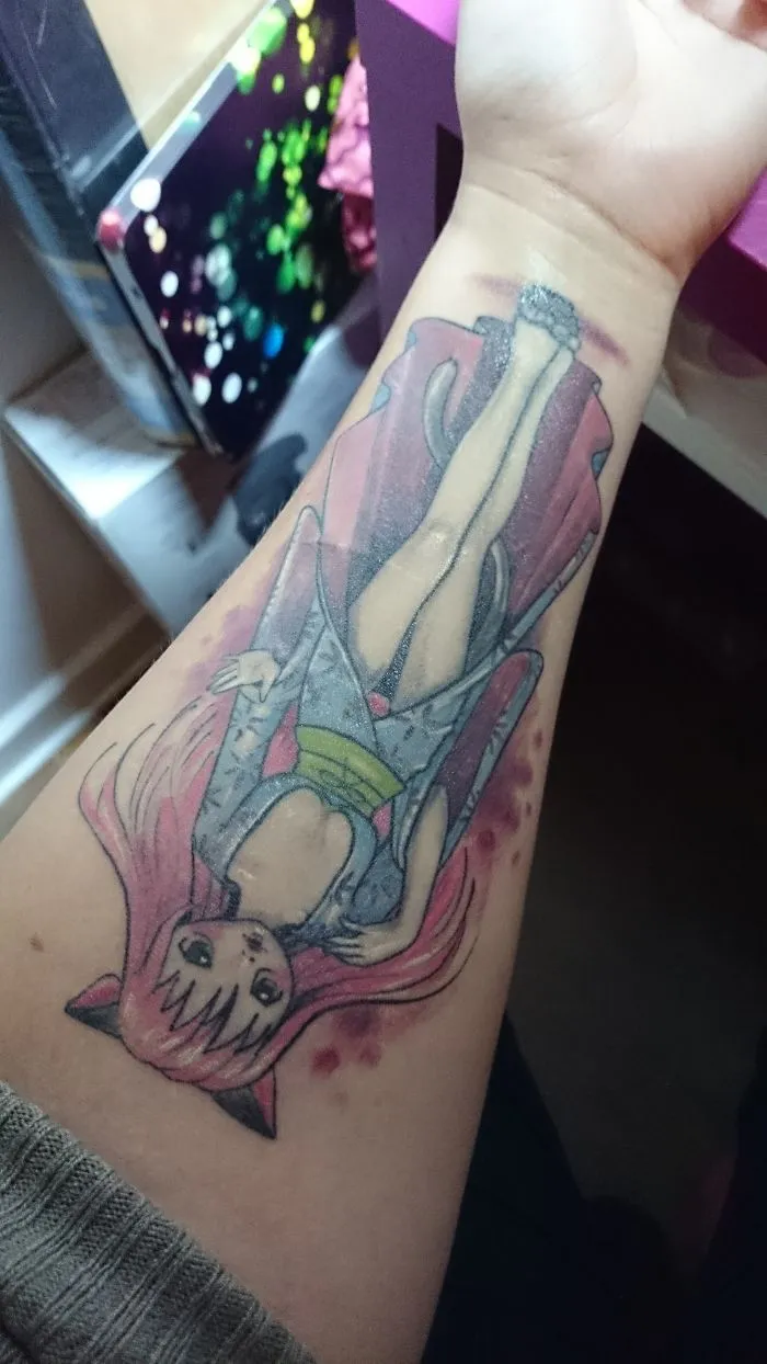Anime character tattoo covering a forearm scar, transforming it into art.