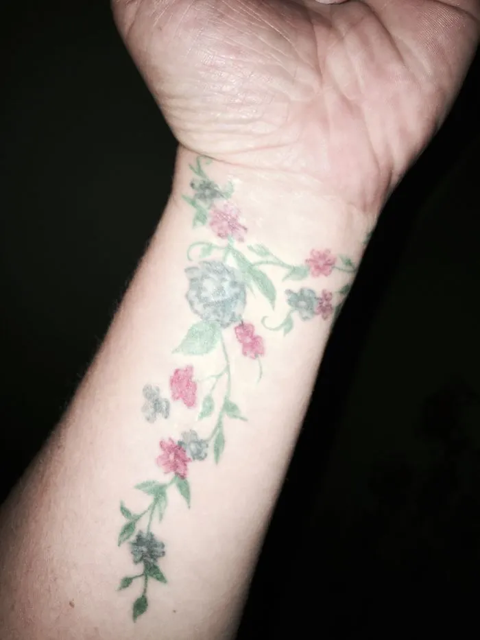 Floral tattoo on wrist creatively covering a scar, showcasing artistic transformation of scars into art.