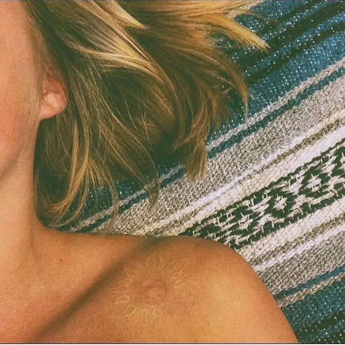 Tattoo art transforming a shoulder scar into a sunburst design.