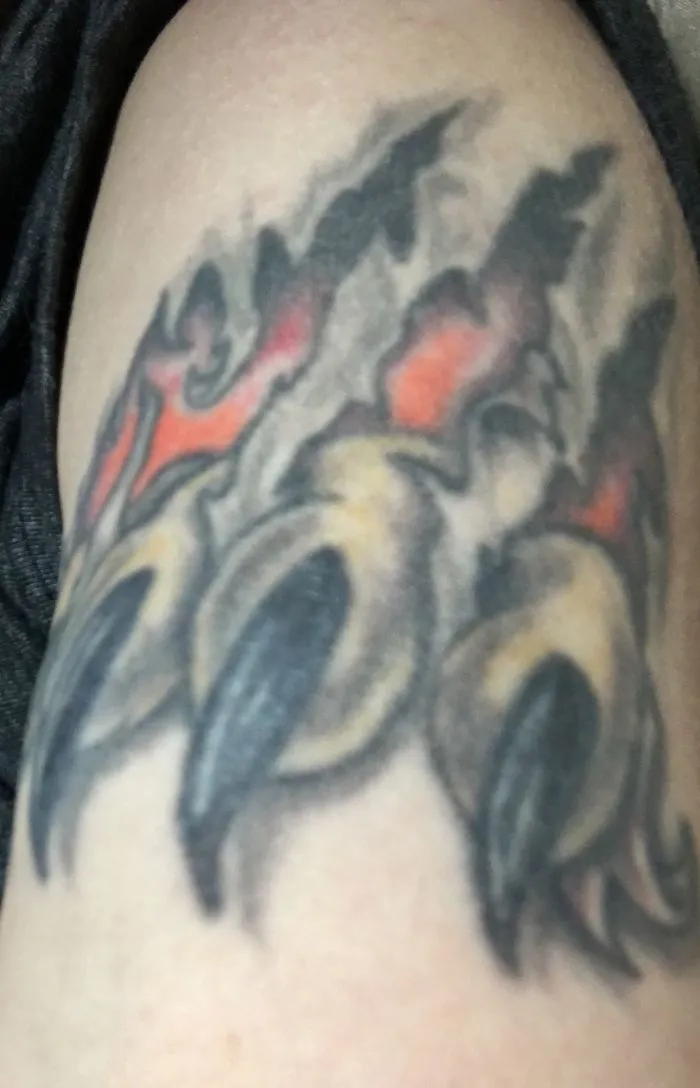 Tattoo art transforming a scar with vibrant colors and claw design.