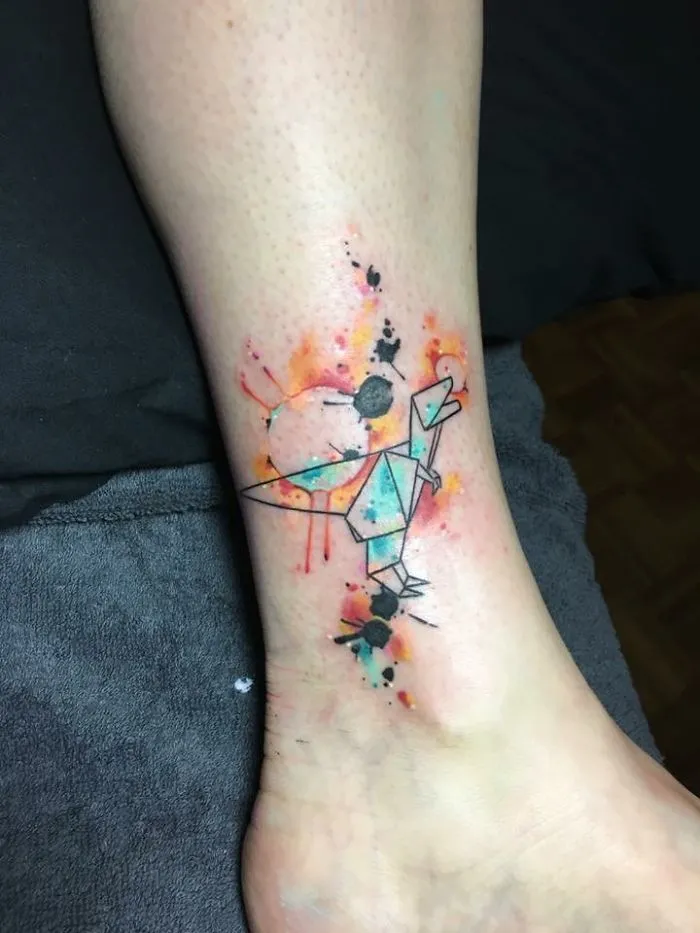Abstract tattoo on a leg, integrating colorful geometric shapes to artistically transform a scar into art.