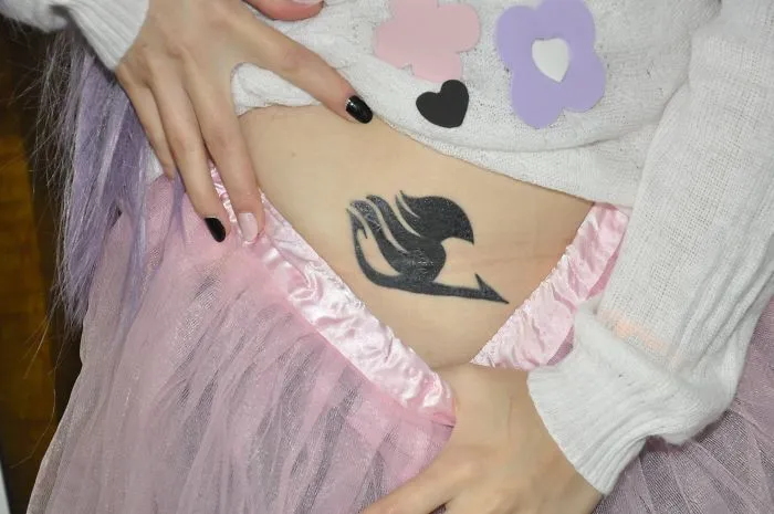Tattoo design on abdomen turns scar into art, surrounded by pink tulle and flower patterns.