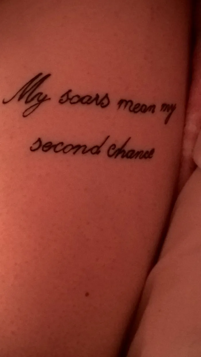 Tattoo saying "My scars mean my second chance" creatively covering a scar.